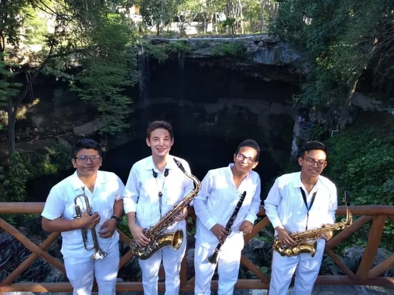 Los cuatro primeros músicos de la ROYAT con sus saxofones y trompeta junto a un cenote